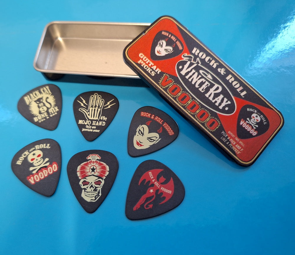Set of guitar picks with a 'Rock & Roll Voodoo' branded tin on a blue surface